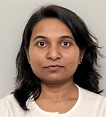 Portrait of a woman with shoulder-length dark hair, wearing a white top, facing the camera with a neutral expression against a light gray background.